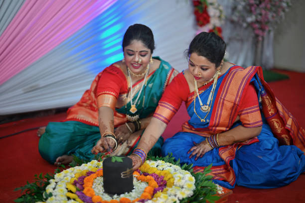 Woman performing puja during Mangalagaur celebration. In this spiritually charged scene, a women, gracefully adorned in traditional attire, performs a sacred pooja ritual. With devotion in her eyes and reverence in her gestures, they delicately offers prayers and floral offerings to a Shivalingam made entirely of vibrant and fragrant flowers.